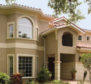 Exterior view of two-story home with tile roofing, elaborate entranceway, and large fiberglass windows.