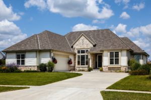 Large suburban home with double-wide driveway, white siding, and three wood-frame windows on front fascade.