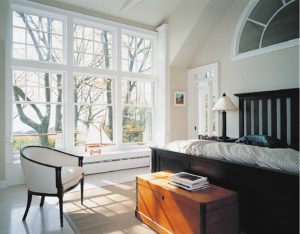 Cozy bedroom with six large vinyl windows overlooking landscape