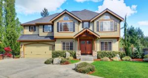 Large home with extended driveway, lush lawn, and expansive house windows.