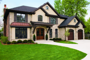 Luxurious single family home with winding driveway, green lawn, and wood frame windows.