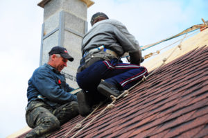 Roofers install asphalt shingles. Contractors laying asphalt shingles and repair roof after hurricane damage.