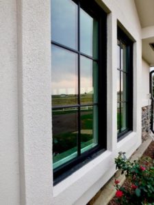 Close-up view of home with white exterior and black-frame fiberglass windows.