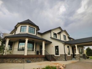 Exterior of luxurious home featuring large wood frame windows. Gray skies in background.